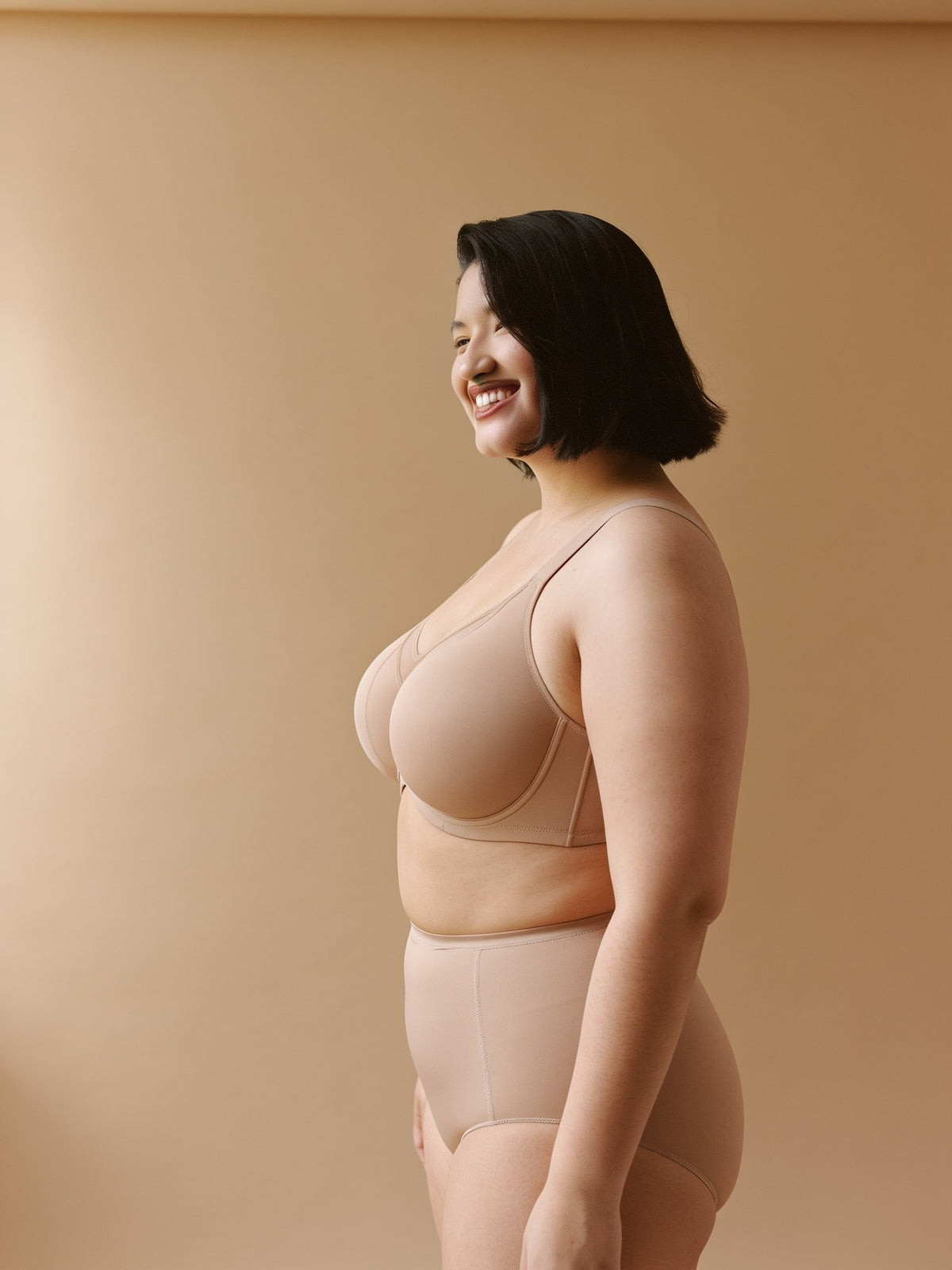 Sostén minimizer beige, vista lateral en modelo con panel lateral y banda bajo busto